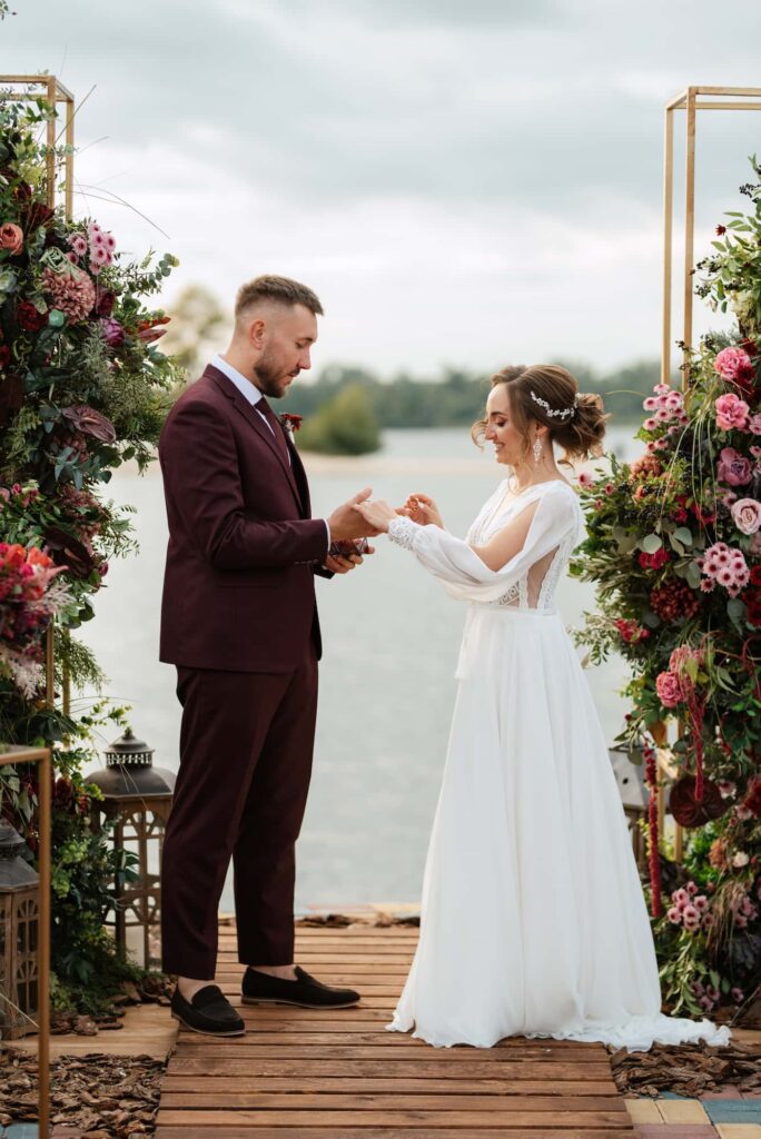 Bride and groom exchanging rings at a lakeside ceremony